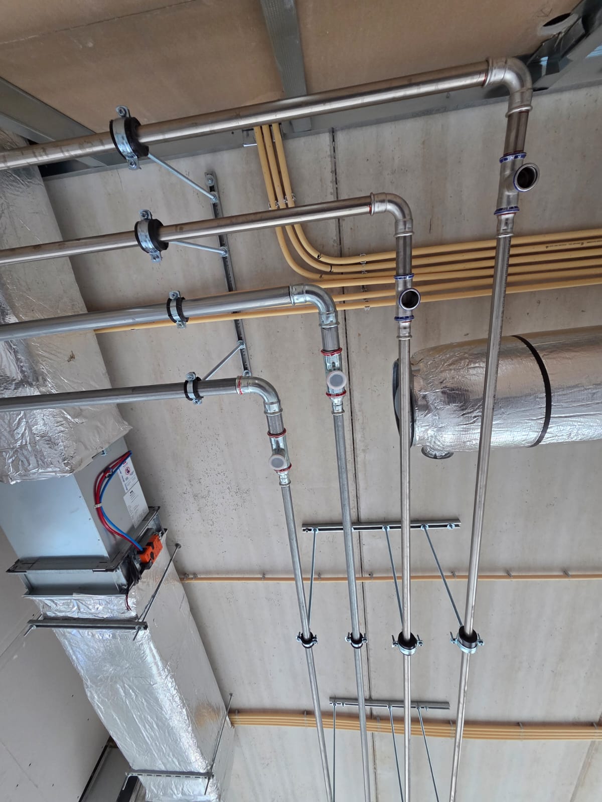 Steel plumbing pipes installed on the ceiling in a modern building.