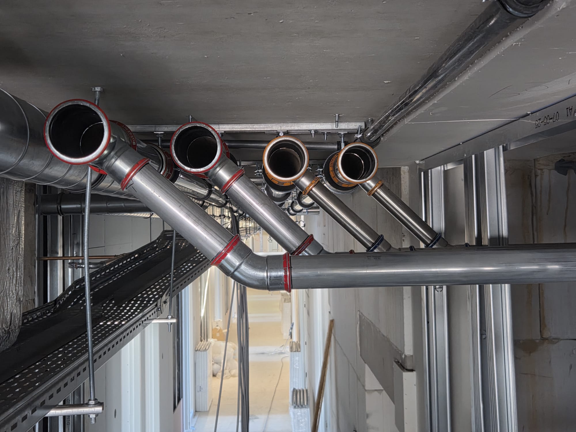 Professionally installed stainless steel drainage system in a technical corridor.